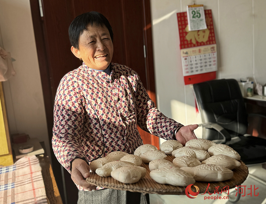 张瑞霞捧着刚出锅的面花，开心地笑着。人民网记者 方童摄